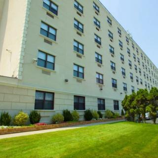 A large apartment building with a well-maintained lawn and surrounding trees.