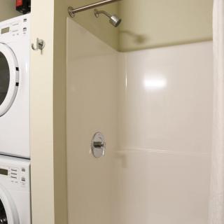 A compact laundry area with a stacked washer and dryer next to a shower.