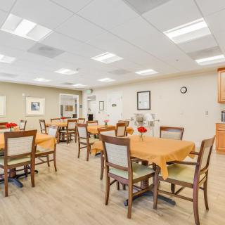 A well-lit dining area with multiple tables and chairs, arranged for a communal setting.