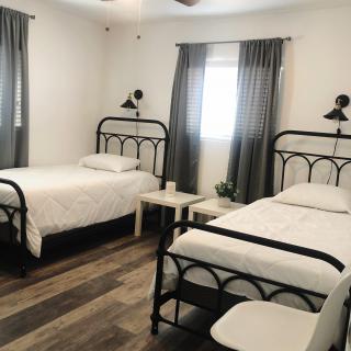 A modern bedroom featuring two twin beds with a minimalist design and wooden flooring.