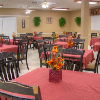 A neatly arranged dining area with tables covered in red tablecloths and floral centerpieces.