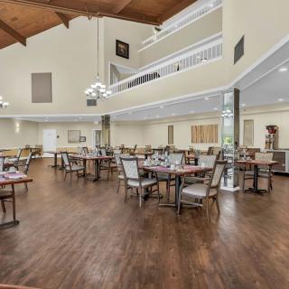 A spacious dining area with neatly arranged tables and chairs on a polished wooden floor.