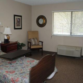 A cozy bedroom with a bed, chair, window, and decorative items.