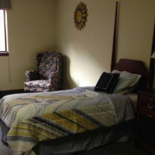 A cozy bedroom with a single bed and an armchair by the window.