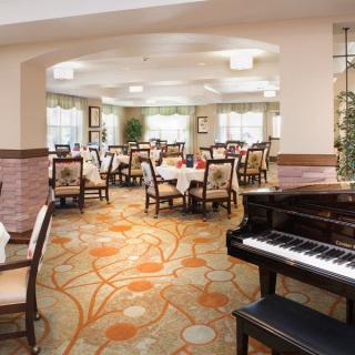 An elegant dining room with a grand piano and beautifully set tables.