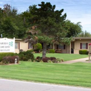A clinic building surrounded by a well-maintained lawn and trees, with a sign in the front.
