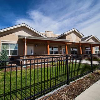 A modern residential building with a black fence and well-maintained landscaping.