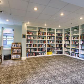 A cozy library with bookshelves lining the walls and a patterned carpet on the floor.