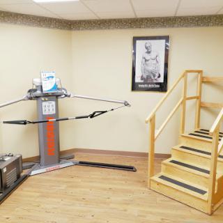 A rehabilitation room featuring exercise equipment and a set of stairs for physical therapy.