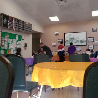 A vibrant community center space with colorful tables, where people are engaged in various activities.