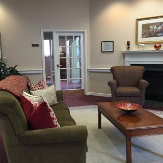 A cozy living room with a couch, armchair, and coffee table in front of a fireplace.