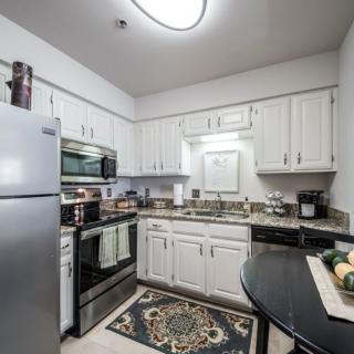 A modern kitchen with white cabinets, a refrigerator, and stainless steel appliances.