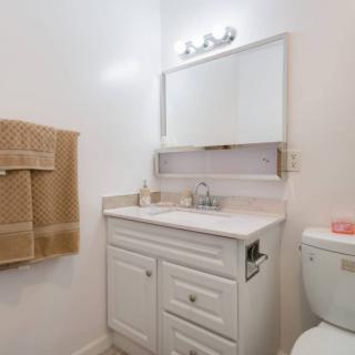 A neatly arranged bathroom with a white vanity, mirror, and towel.