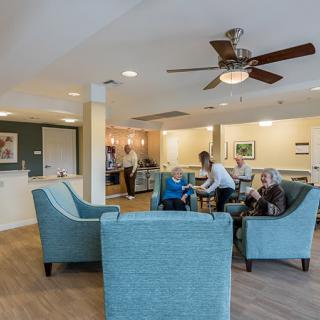 People interacting in a cozy living room setting with comfortable armchairs and soft lighting.