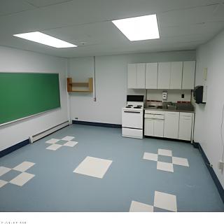 An empty classroom with a kitchenette, featuring a chalkboard and tiled flooring.