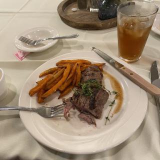A delicious plate of beef with sweet potato fries and iced tea.