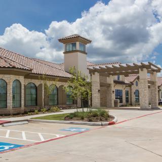 A modern building with a tower and arched windows under a cloudy sky.