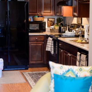 A cozy kitchen with dark wood cabinets, a black fridge, and various appliances on the countertop.