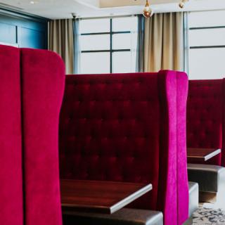 A modern restaurant interior with plush red booth seating.