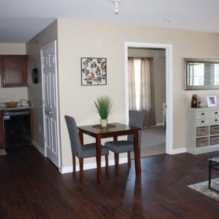 A cozy apartment interior featuring a small dining table with two chairs, leading to a kitchen and living area.