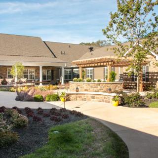A well-maintained garden and patio area outside a large building with landscaped pathways.