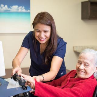 A healthcare worker assisting a smiling elderly woman.