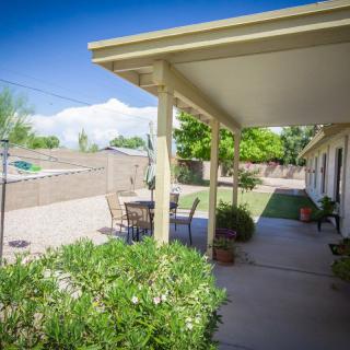 A sunny backyard patio with outdoor furniture and lush greenery.