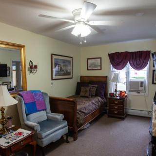 A cozy bedroom with a bed, armchair, and various decorations.