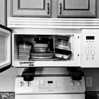 A view of a kitchen microwave filled with plates and cooking items.