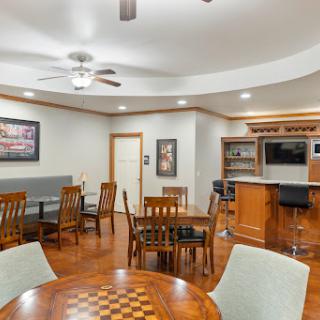 A cozy and inviting dining area featuring wooden furniture, a ceiling fan, and a bar, perfect for gatherings and leisure activities.