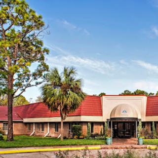 A welcoming entrance to a modern building surrounded by lush greenery.