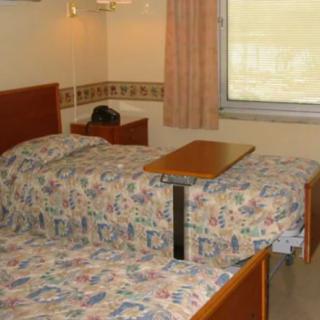 A hospital room featuring twin beds with a small table in between.