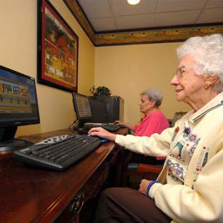 Two elderly people using computers in a learning environment.