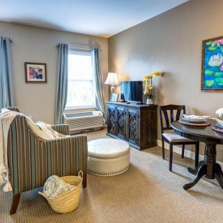 A cozy living room with comfortable seating, a table, and artwork on the walls.