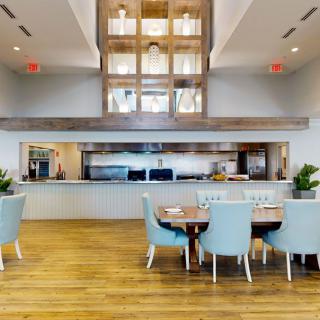 A modern open-concept kitchen and dining area with blue chairs and wood flooring.