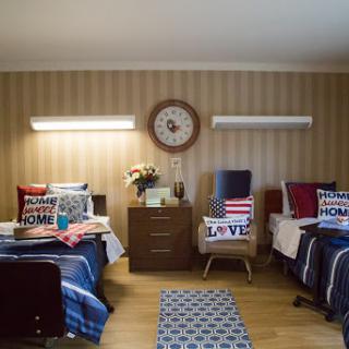 A cozy shared bedroom with two beds, decorated with patterned pillows and a warm ambiance.
