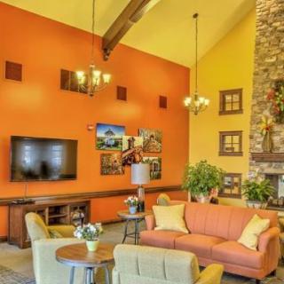 A cozy living room featuring a vibrant orange wall with a flat-screen TV, comfortable seating, and a stone fireplace.