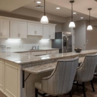 A modern kitchen with pendant lighting and a spacious countertop featuring elegant bar stools.