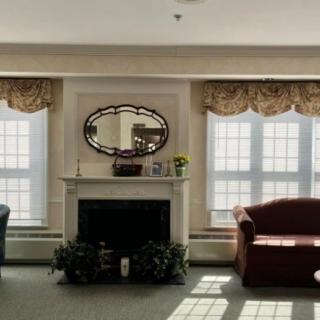 A cozy living room with a fireplace, sofas, and large windows letting in natural light.