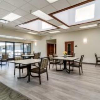 A modern dining area with multiple tables and chairs, well-lit by natural light.