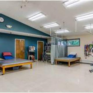 A spacious physical therapy room equipped with treatment beds and exercise equipment.