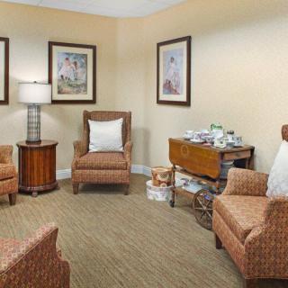 A cozy living room with armchairs, a lamp, and wall art.