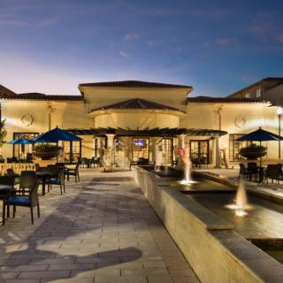 An elegant outdoor dining area with fountains and umbrellas at dusk.