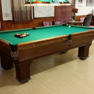 A classic wooden pool table in a game room setting.
