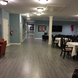A hallway leading to a dining area with tables and chairs, featuring modern lighting and decor.
