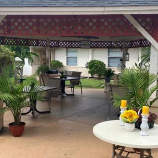 An inviting outdoor patio area with a gazebo, featuring tables, chairs, and lush plants.