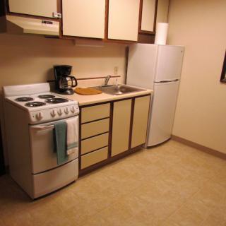 A small, minimalist kitchen with basic appliances and cabinetry.