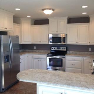 A modern kitchen with white cabinets and stainless steel appliances.