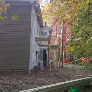 A side view of a house undergoing construction, surrounded by autumn foliage.
