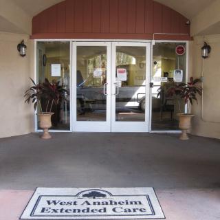 Entrance of West Anaheim Extended Care with glass doors and potted plants.